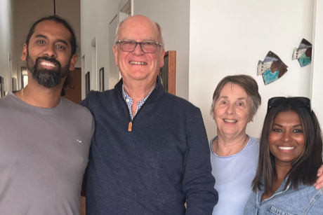 Four people posing together indoors, smiling at the camera.